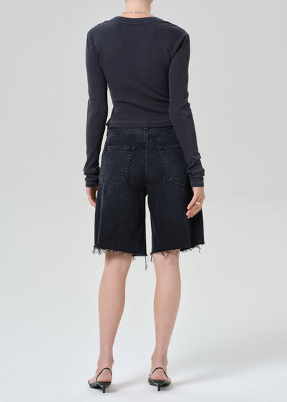 Person wearing a charcoal long-sleeve shirt and blank denim shorts on a grey background