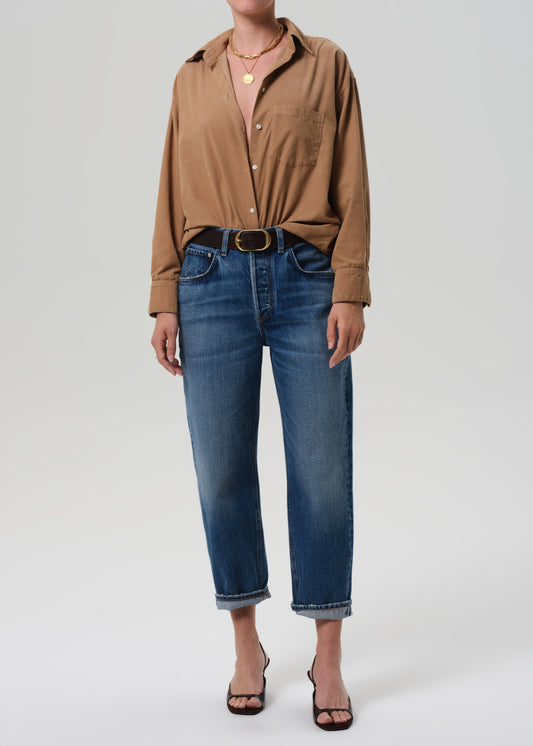 Person wearing a brown shirt and blue jeans on a plain background