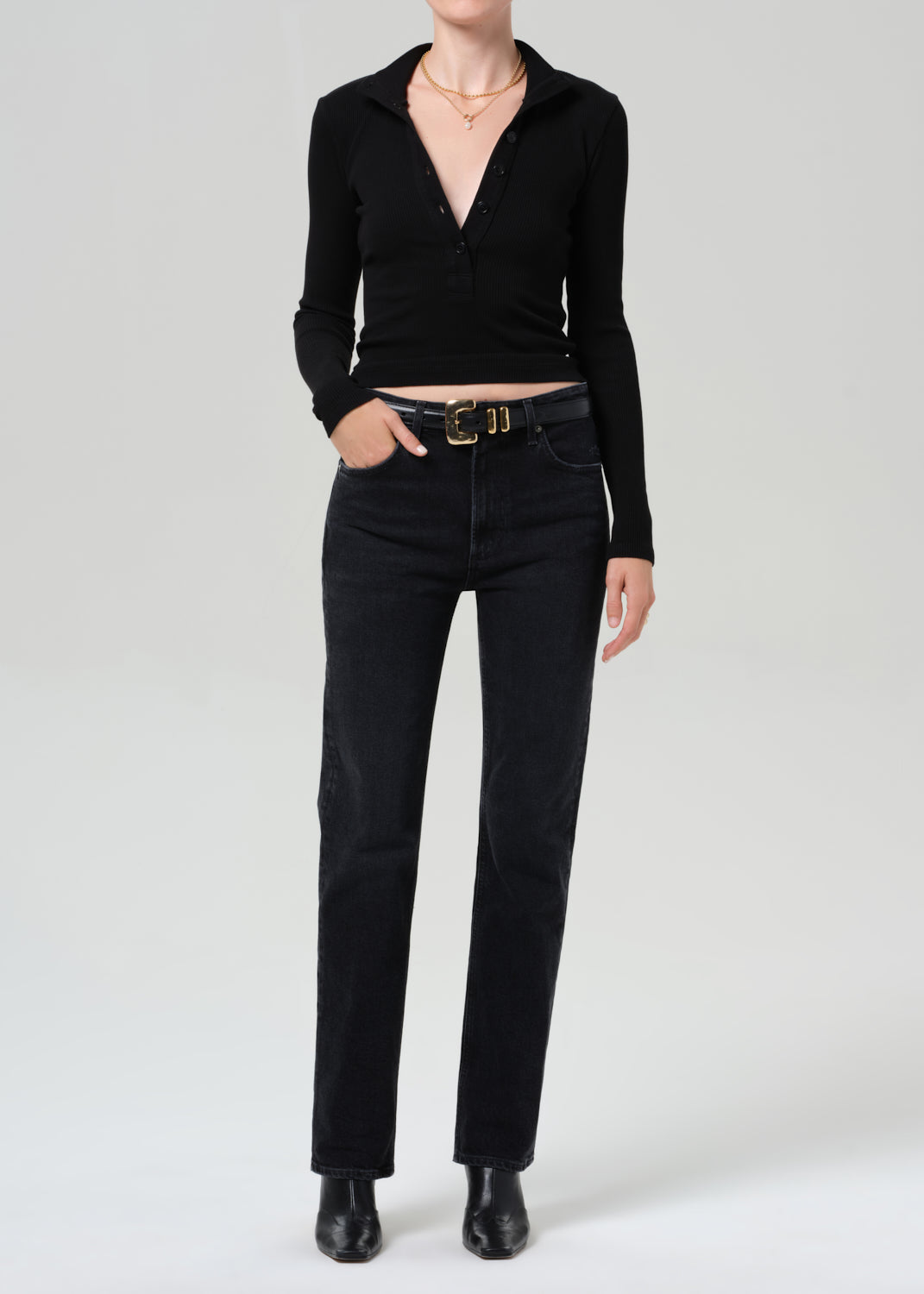 Person wearing a black sweater and black jeans on a plain background