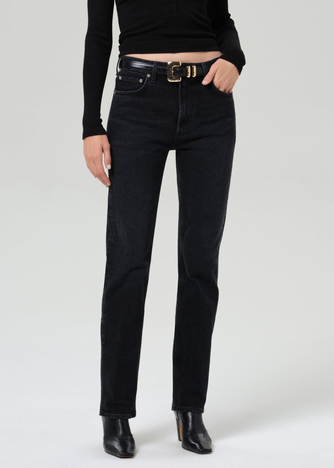 Person wearing a black sweater and black jeans on a plain background