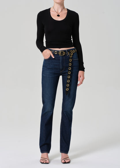 Person wearing blue jeans with decorative buttons and a black top on a  plain background