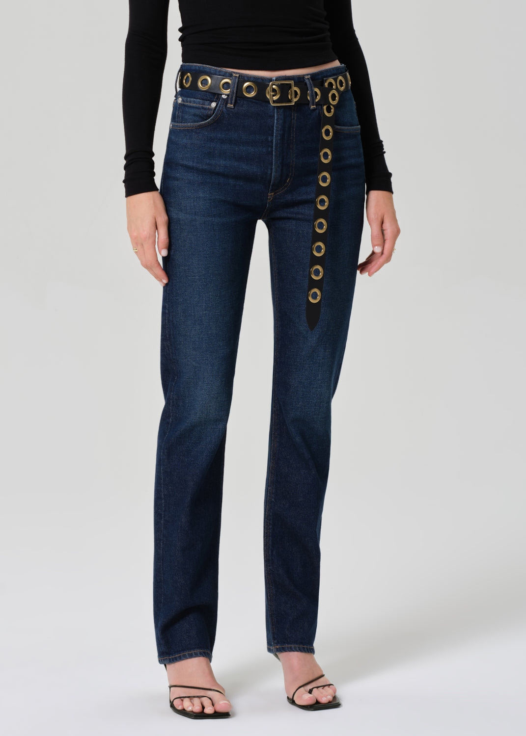 Person wearing blue jeans with decorative belt on a white background