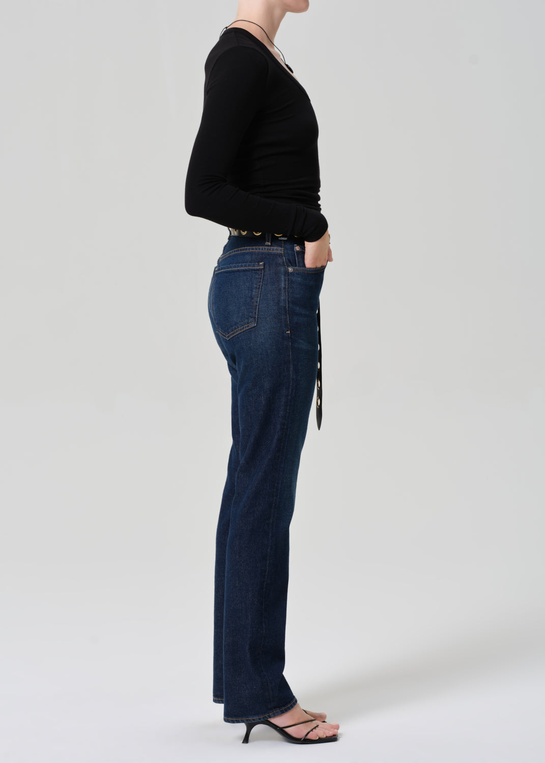 Person wearing dark blue jeans and a black top on a white background
