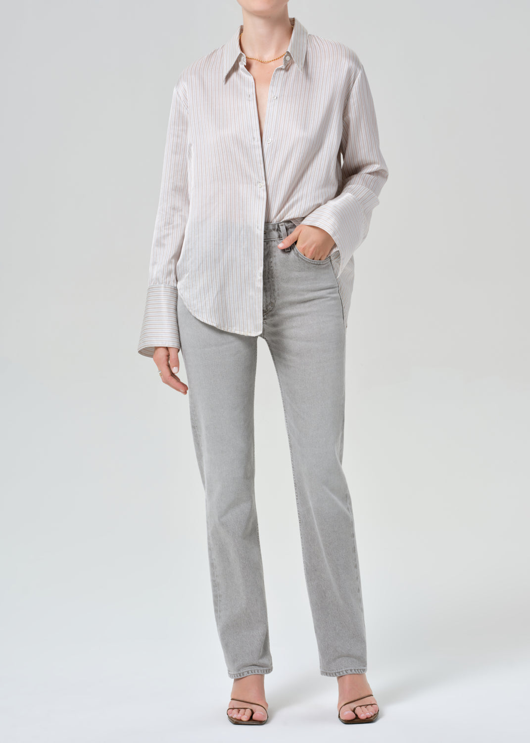 Person wearing a light gray shirt and pants on a grey background