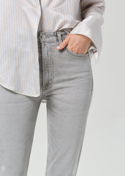 Person wearing a light gray stripe shirt and jeans on a grey background