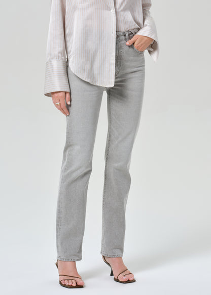 Person wearing a light gray stripe shirt and jeans on a grey background