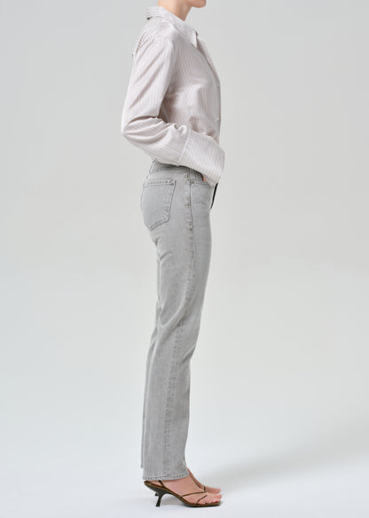 Person wearing a light gray stripe shirt and jeans on a grey background