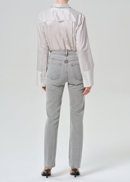 Person wearing a light gray stripe shirt and jeans on a grey background