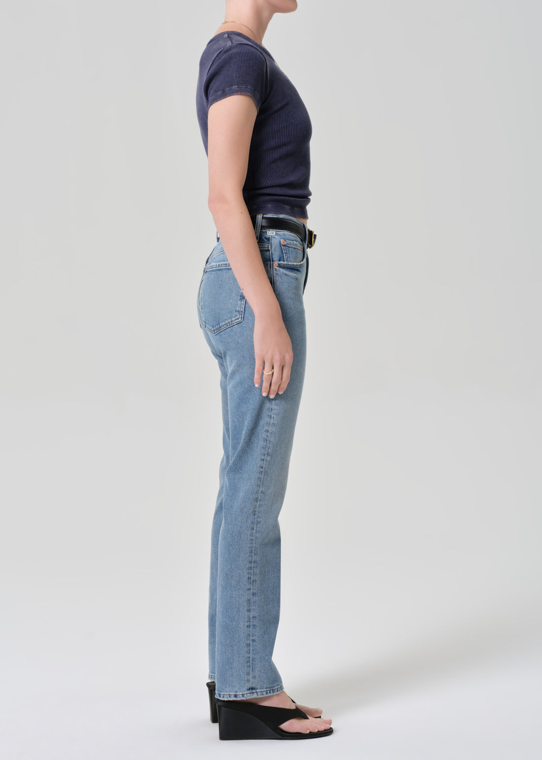 Person wearing a navy t-shirt and light blue jeans on a plain background