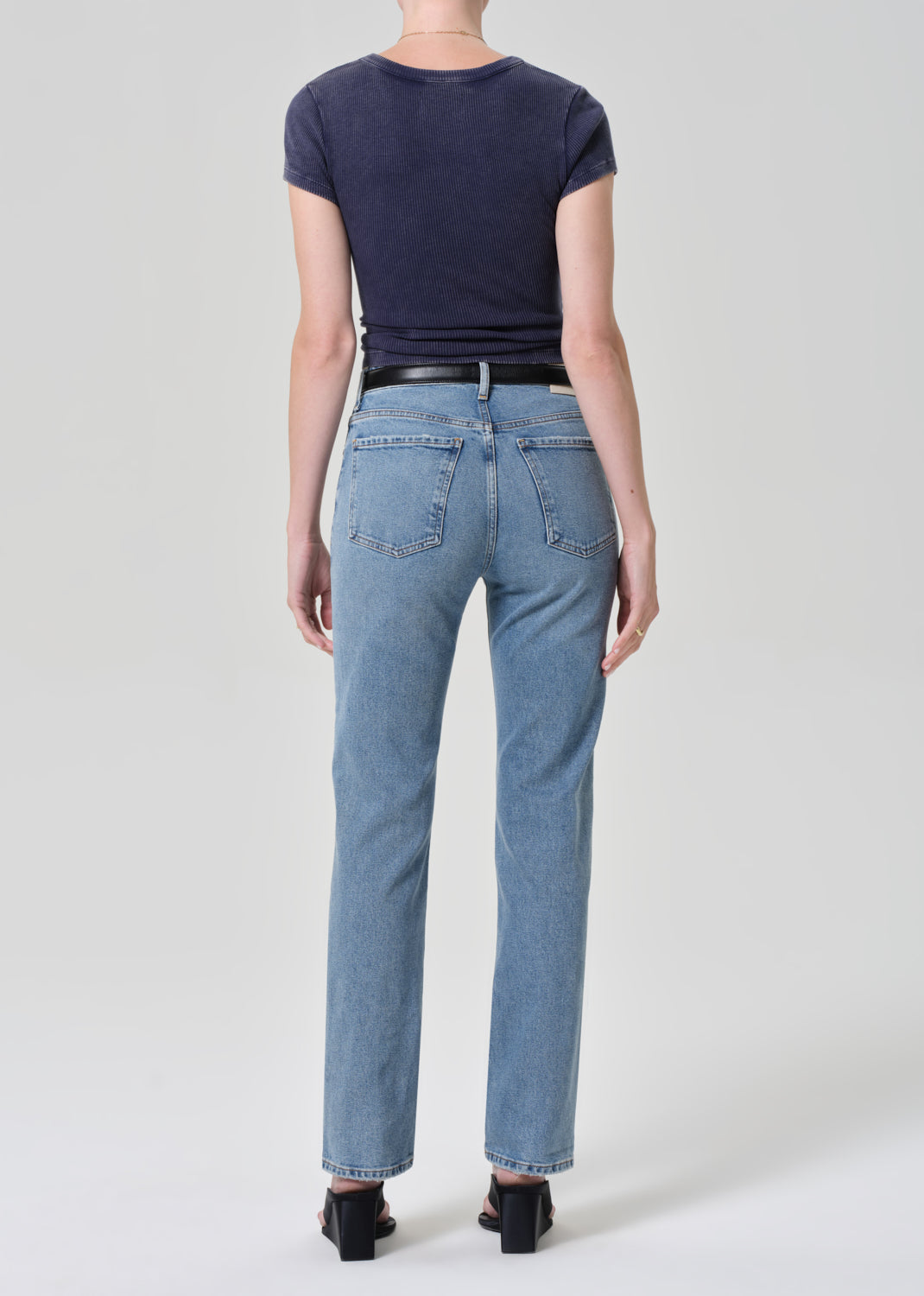 Person wearing a navy t-shirt and light blue jeans on a plain background