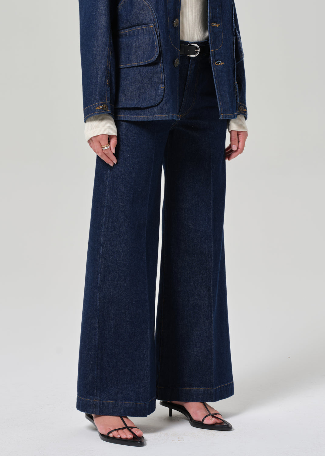 Person wearing a blue denim outfit with wide-leg jeans on a white background