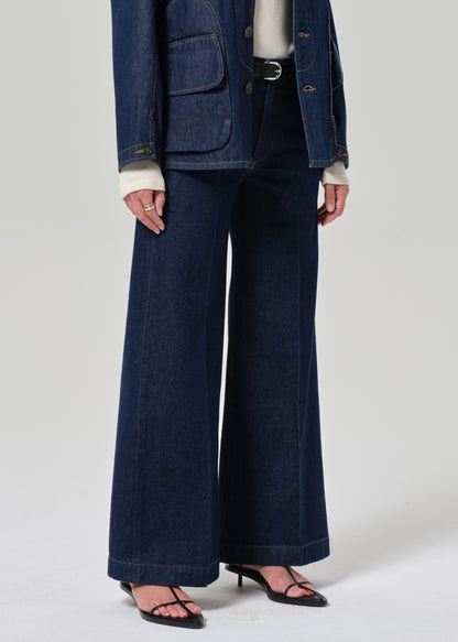 Person wearing a blue denim outfit with wide-leg jeans on a white background