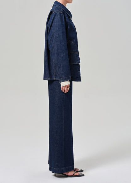 Person wearing a dark denim jacket and wide-leg jeans on a white background