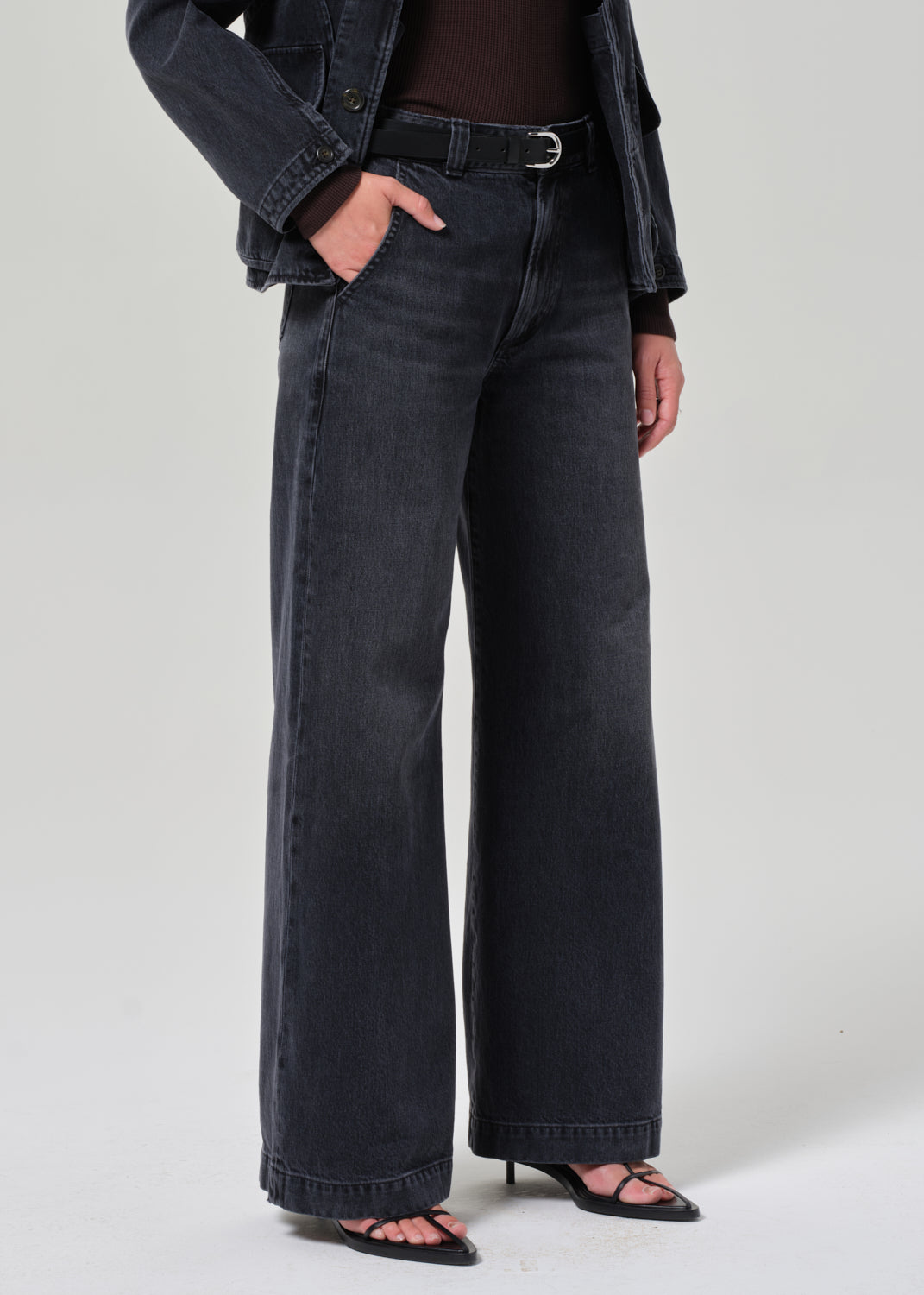 Person wearing washed black wide-leg jeans on a plain background