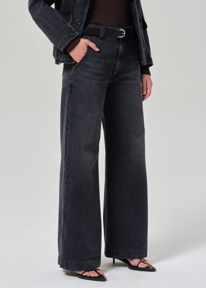 Person wearing washed black wide-leg jeans on a plain background