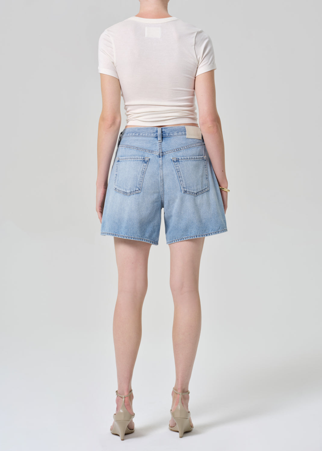 Person wearing light blue denim shorts and a white top on a plain background