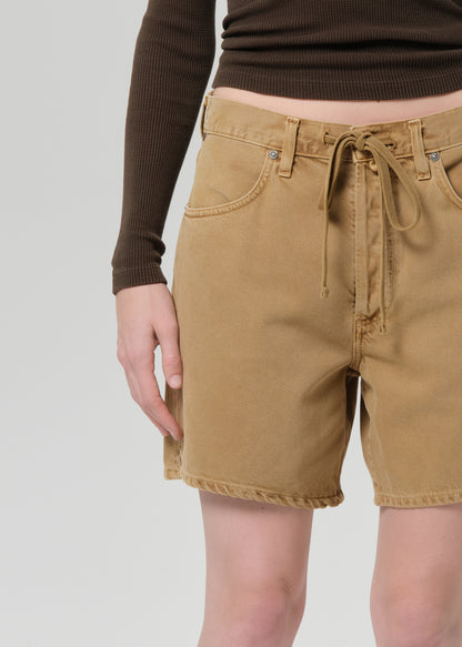 Person wearing a brown long-sleeve shirt and tan shorts on a plain background
