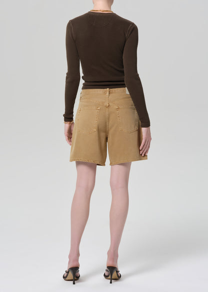 Person wearing a brown long-sleeve shirt and tan shorts on a plain background