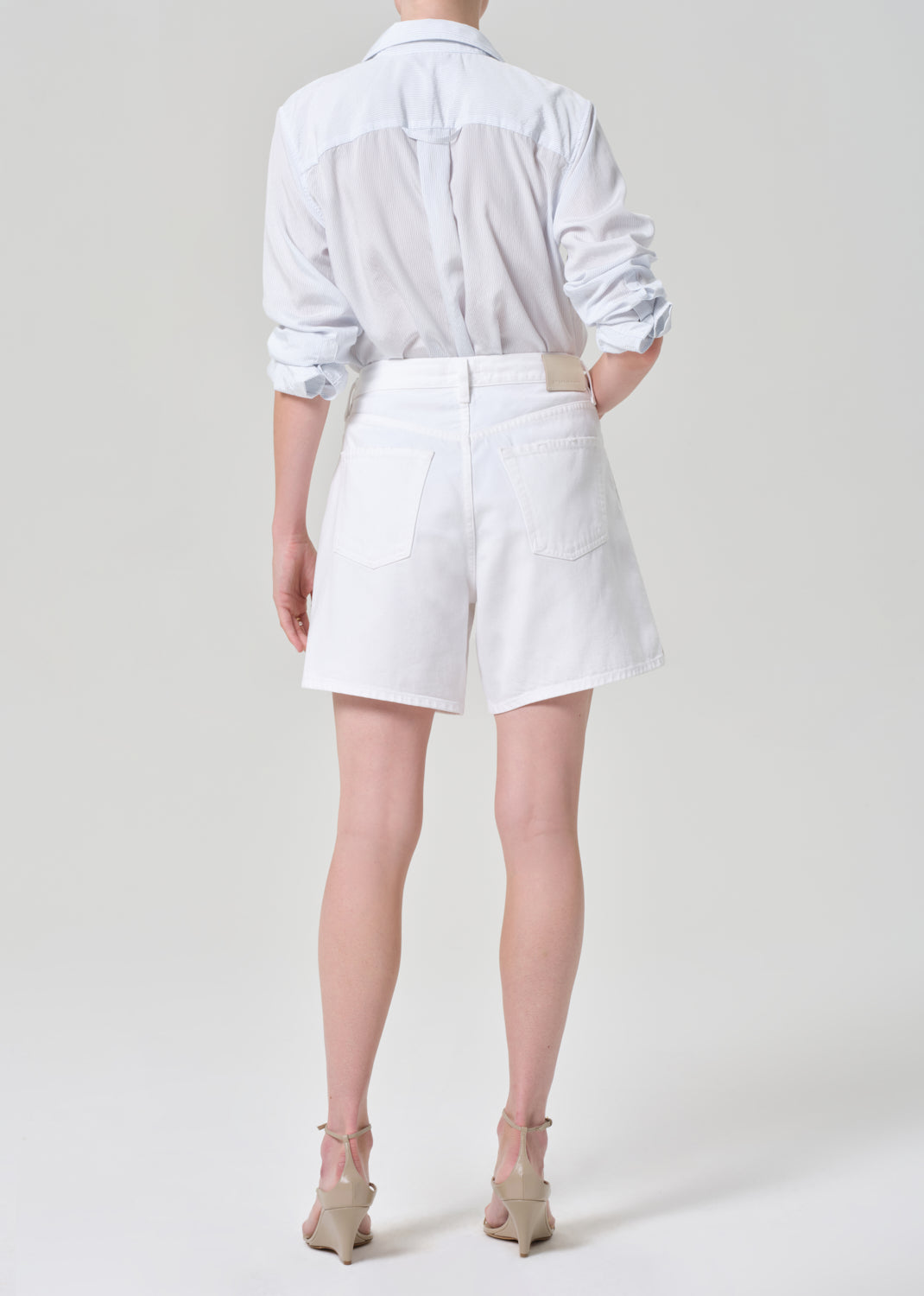 Person wearing a white button up shirt with white denim short