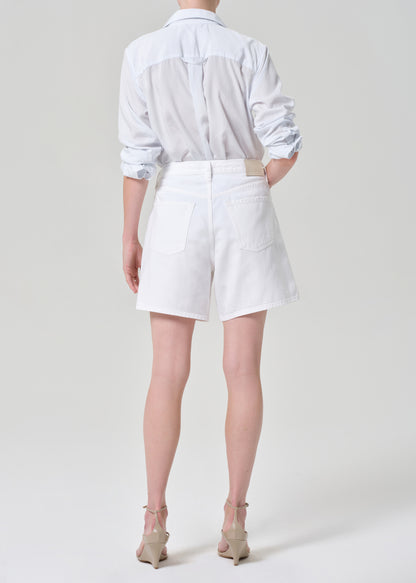 Person wearing a white button up shirt with white denim short