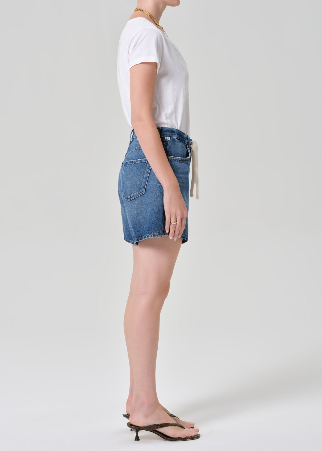 Person wearing a white t-shirt and denim shorts on a plain background