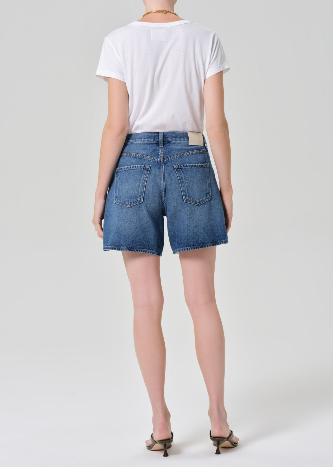 Person wearing a white t-shirt and denim shorts on a plain background