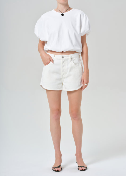 Person wearing a white top and white shorts on a plain background