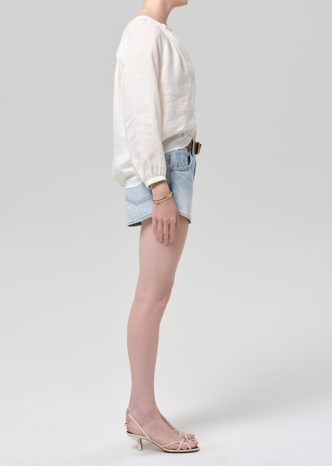 Person wearing a white top and light blue denim shorts on a plain background
