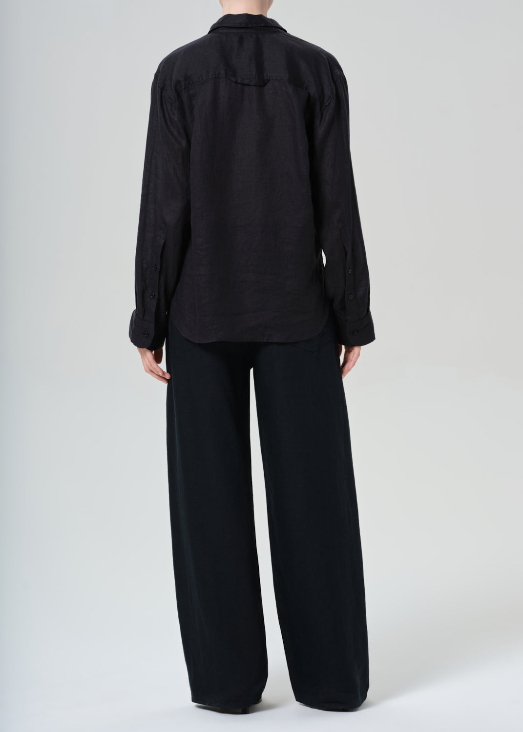 Person wearing a black outfit with wide-leg pants on a white background