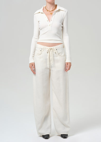 Person wearing a white cropped top and wide-leg pants on a plain background