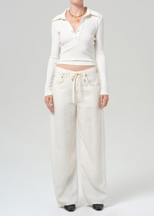 Person wearing a white cropped top and wide-leg pants on a plain background