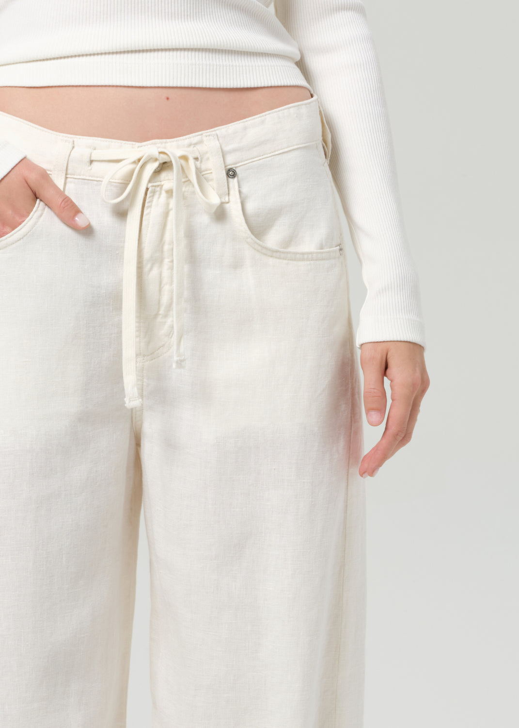 White pants with a drawstring waist on a plain background