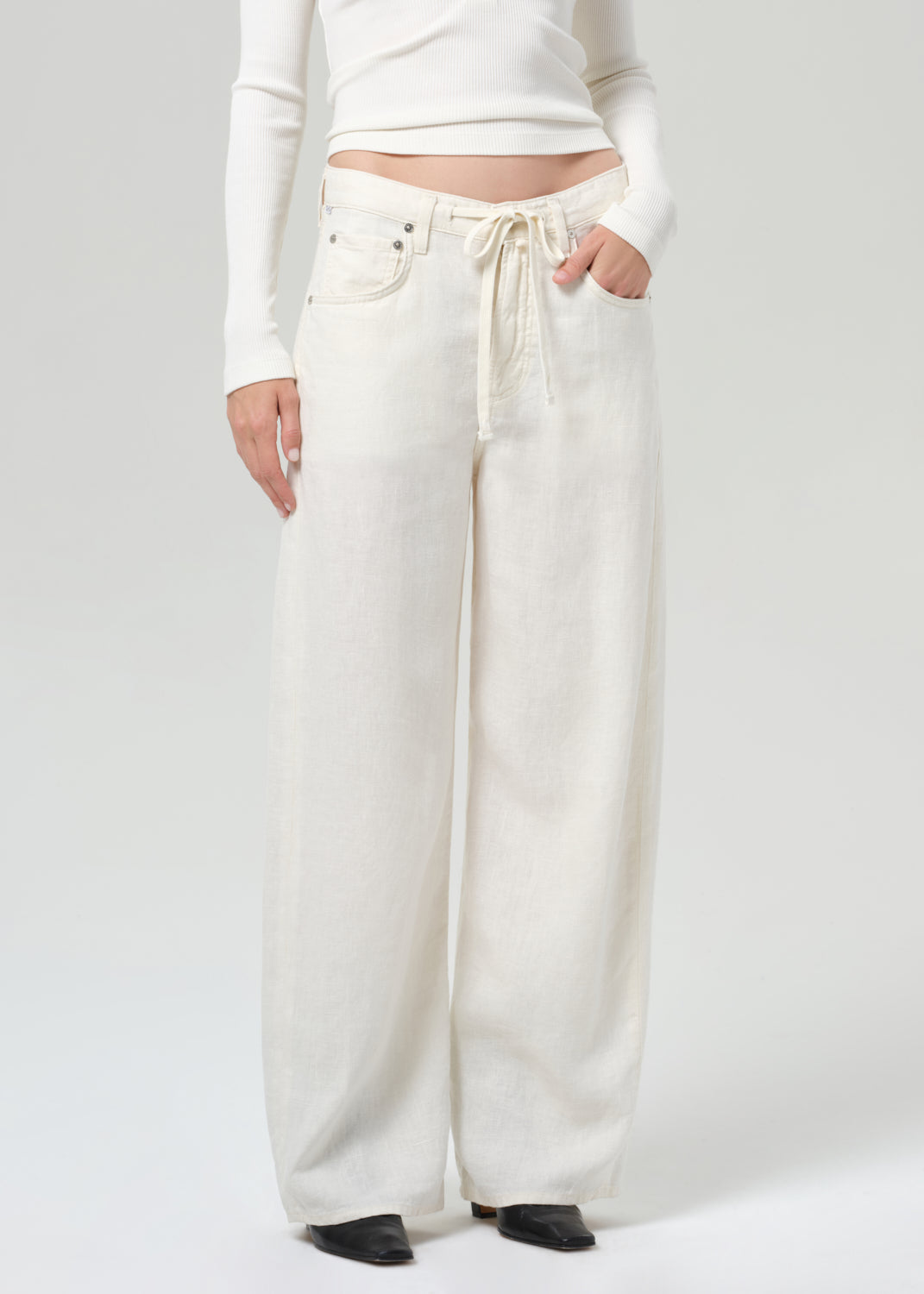 Person wearing white wide-leg pants with a drawstring on a plain background