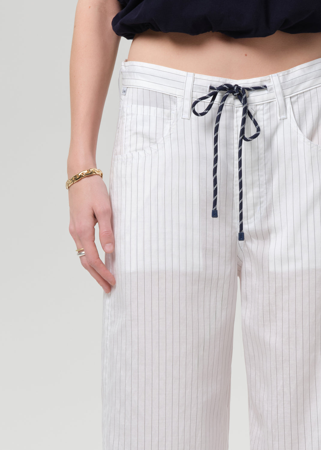 White pleated pants with a drawstring on a plain background
