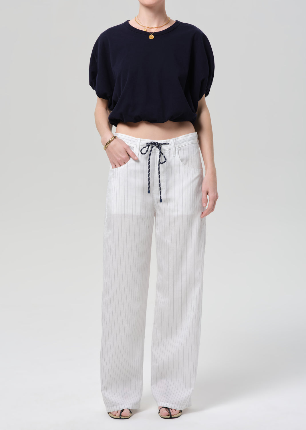 Person wearing a black top and white striped pants on a plain background