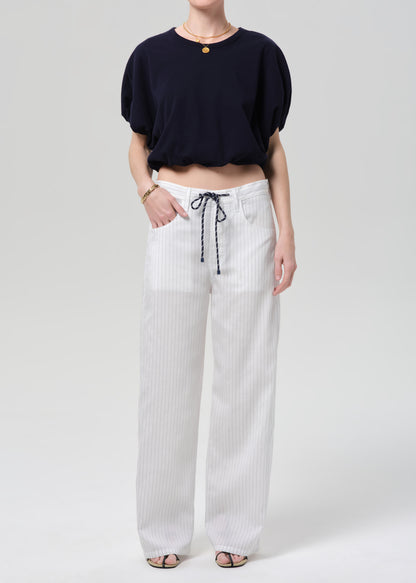 Person wearing a black top and white striped pants on a plain background
