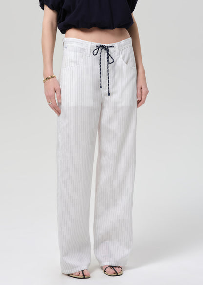 Person wearing white striped pants with a drawstring on a plain background