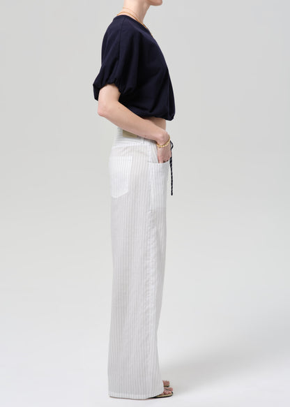 Person wearing a navy top and white striped pants on a plain background