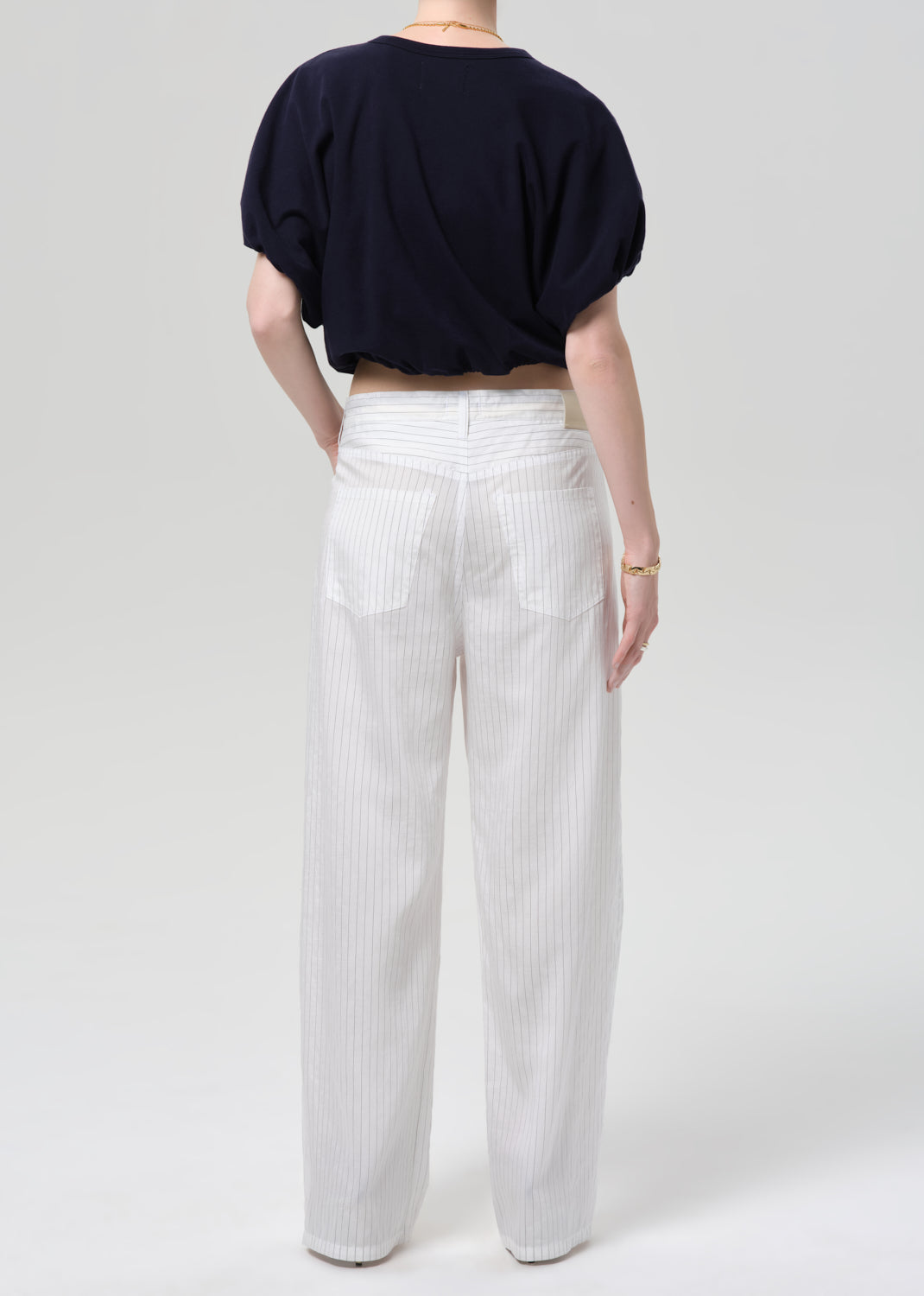Person wearing a navy top and white striped pants on a plain background