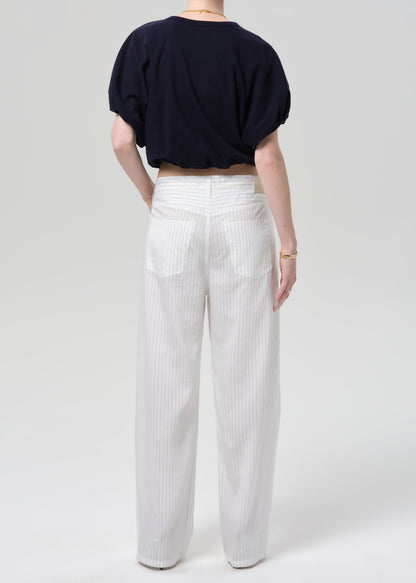 Person wearing a navy top and white striped pants on a plain background