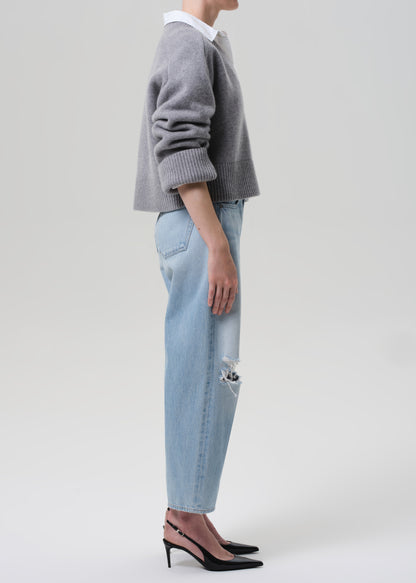 Person wearing a gray sweater and light blue jeans on a plain background