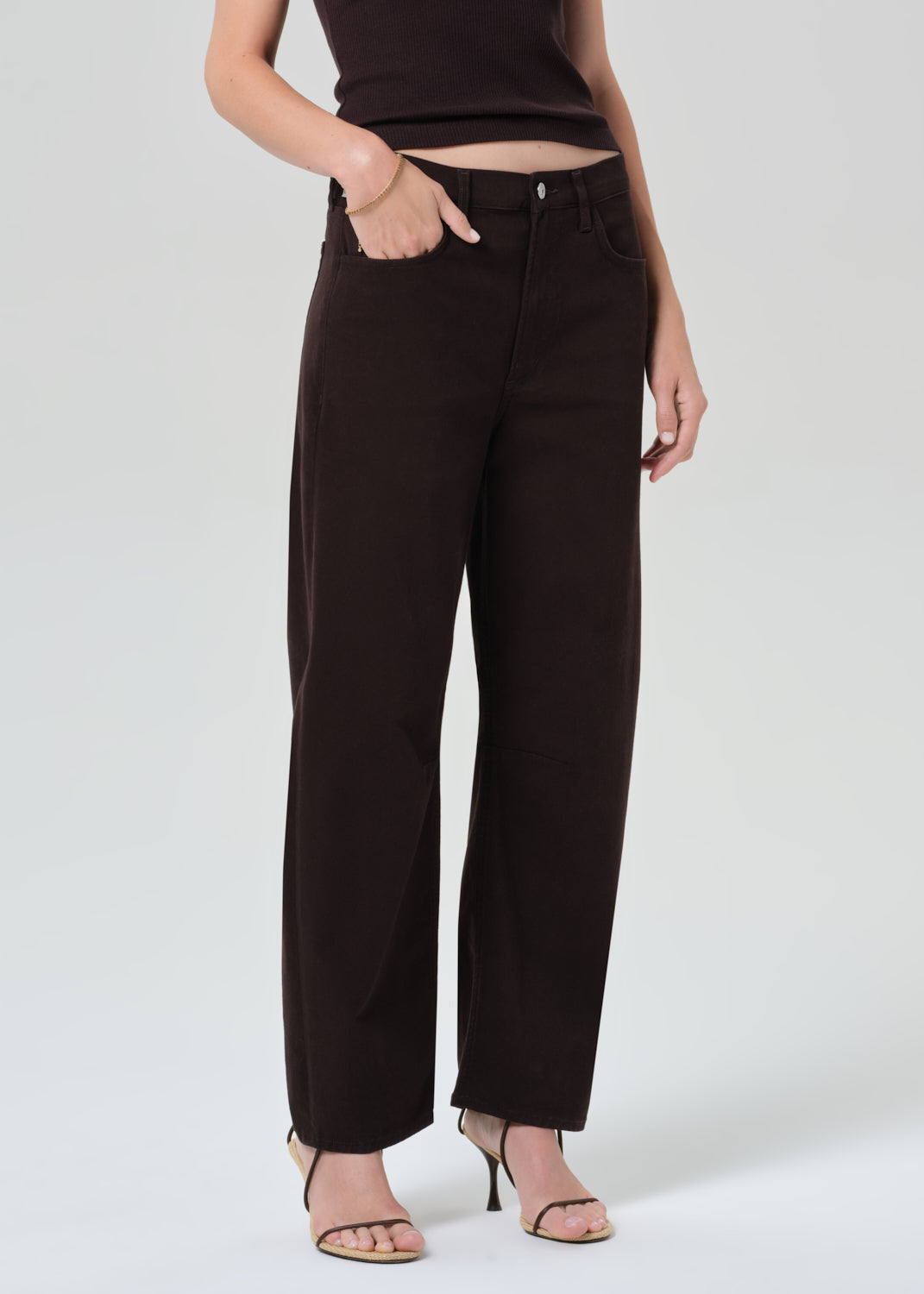 Person wearing a brown t-shirt and brown pants on a grey background