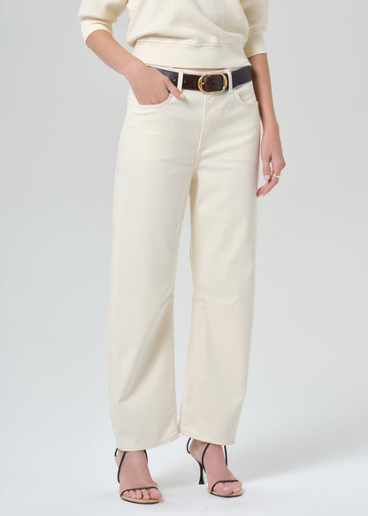 Person wearing a cream sweater and cream pants on a plain background