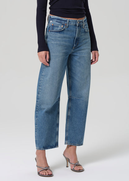 Person wearing blue jeans and a navy top on a grey background