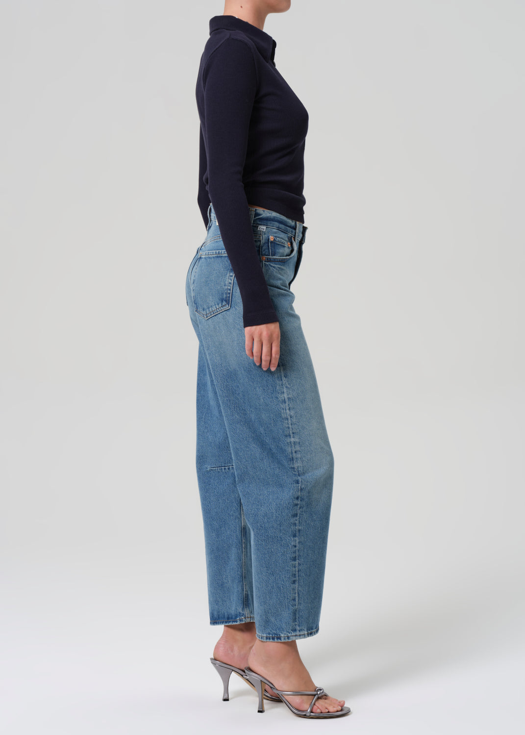 Person wearing blue jeans and a navy top on a grey background