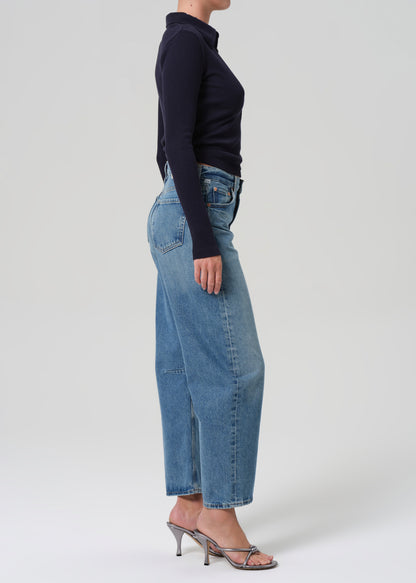 Person wearing blue jeans and a navy top on a grey background