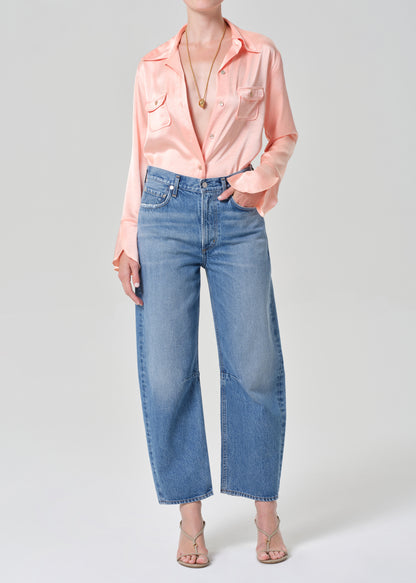 Person wearing a pink shirt and blue jeans on a grey background