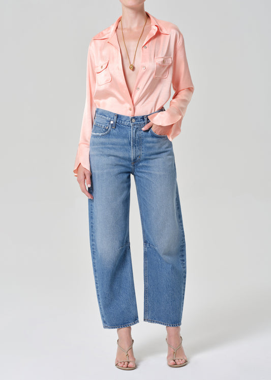 Person wearing a pink shirt and blue jeans on a grey background