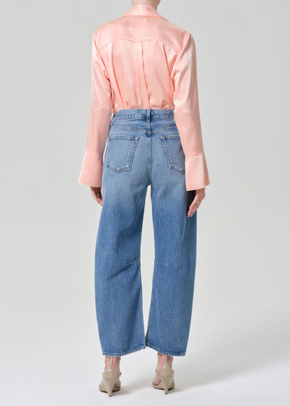 Person wearing a pink shirt and blue jeans on a grey background