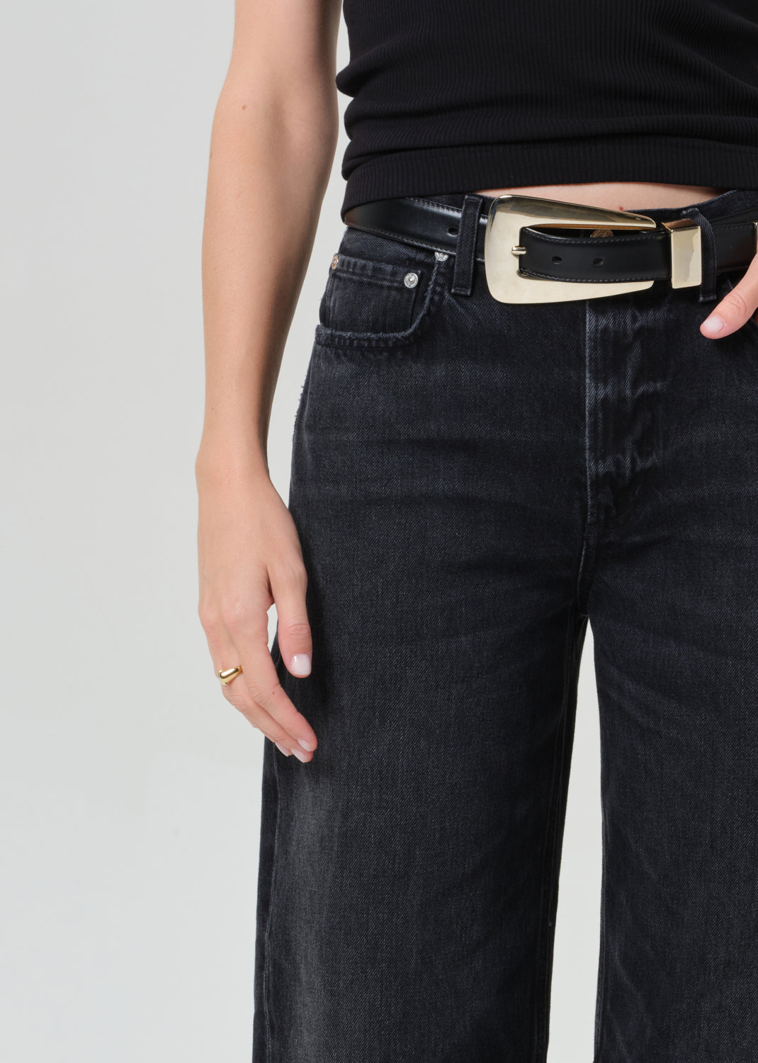 Person wearing a black sleeveless top and black jeans on a plain background